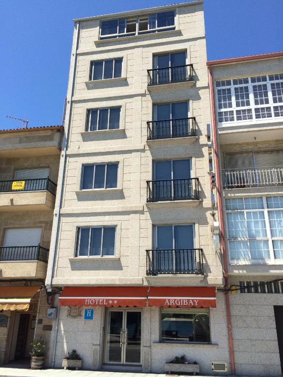a tall white building with balconies on a street at Hotel Argibay in O Grove