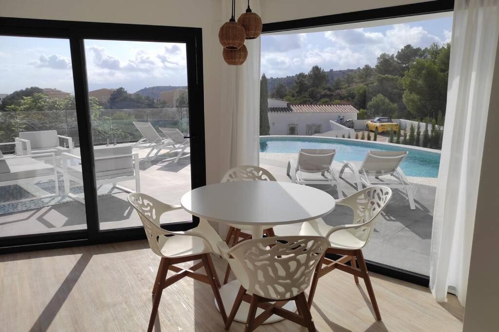 uma mesa branca e cadeiras num quarto com piscina em Precioso apartamento en una villa con piscina en Cumbre del Sol Moraira Benitachell em Cumbre del Sol