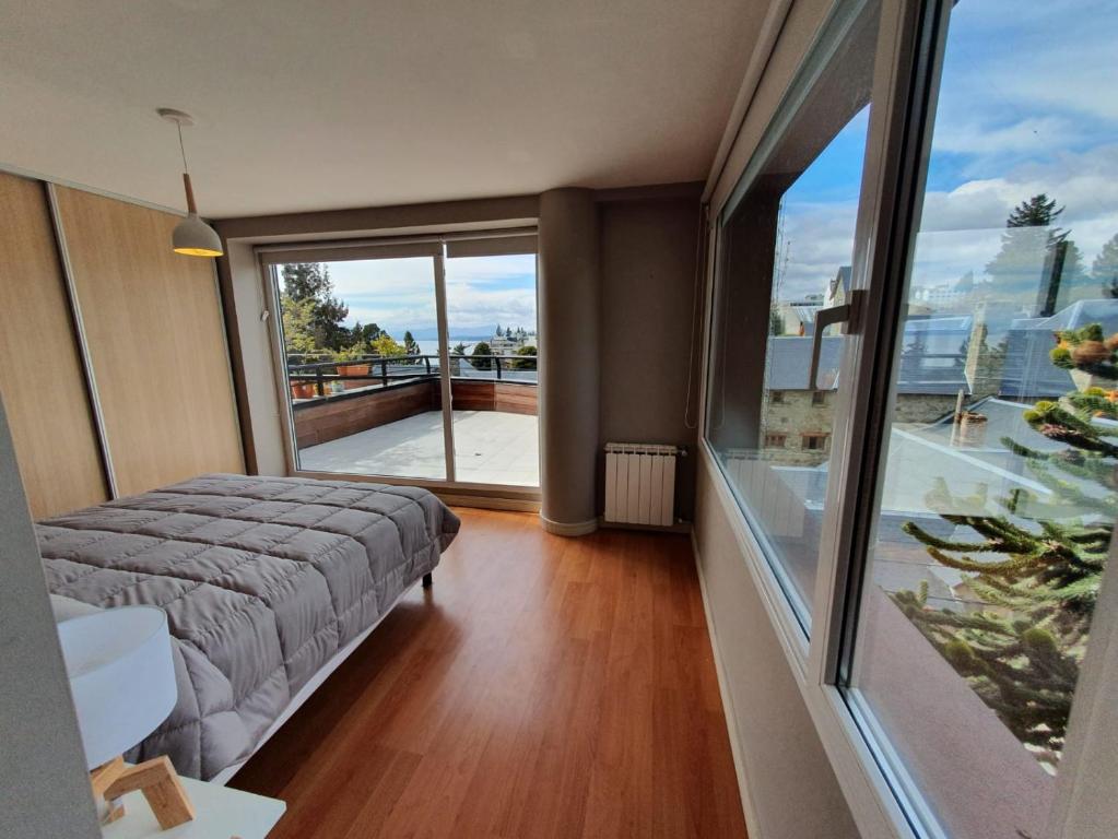 Un dormitorio con una cama y una ventana grande. en Departamento Bariloche centro, en San Carlos de Bariloche