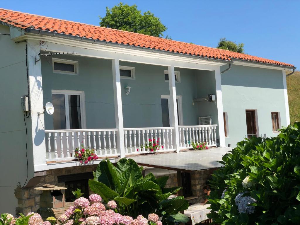 a white house with a porch and flowers at Casa la palmera in Gormazo