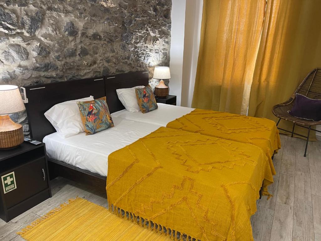 um quarto com uma cama com um cobertor amarelo em Esmeralda Holidays Apartments no Funchal