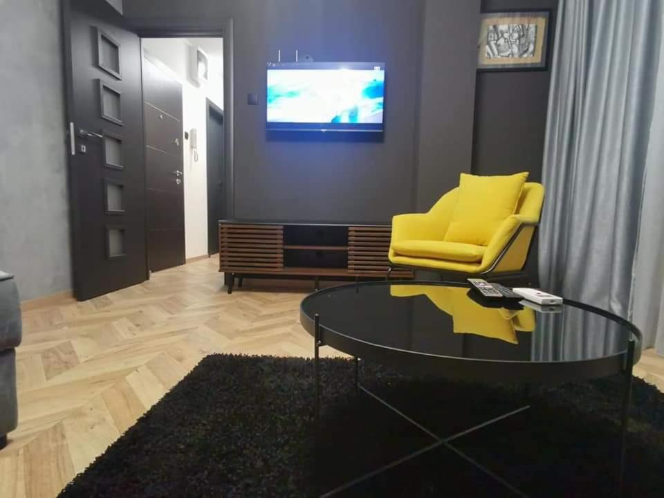 ein Wohnzimmer mit einem gelben Stuhl und einem Glastisch in der Unterkunft City-centar in Banja Luka