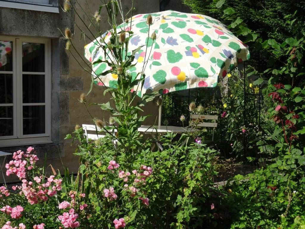 ein Polka-Punkt-Schirm in einem Garten mit Blumen in der Unterkunft Bévau - B&B bio 