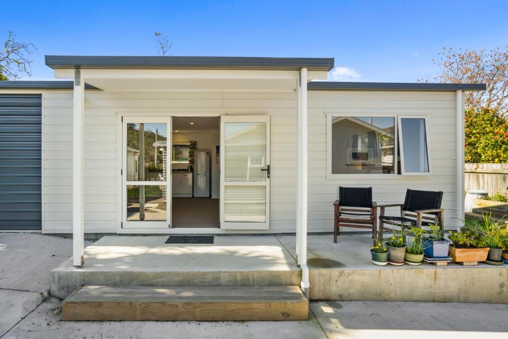 a white house with a porch and a chair at Karori Kabin - Karori Holiday Home in Wellington