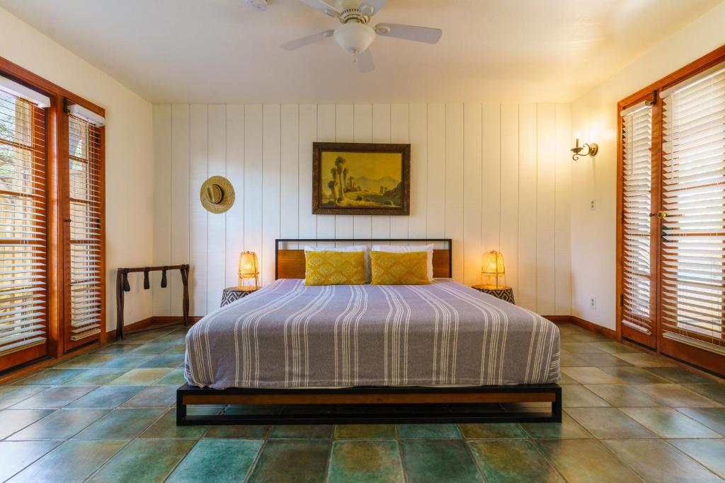 a bedroom with a bed and two lamps and two windows at The Good House- Hot Spring Hideaway in Desert Hot Springs