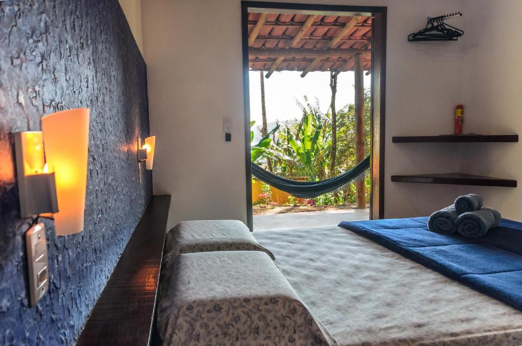 a bedroom with a bed and a window with a hammock at Fauna in Praia do Bananal