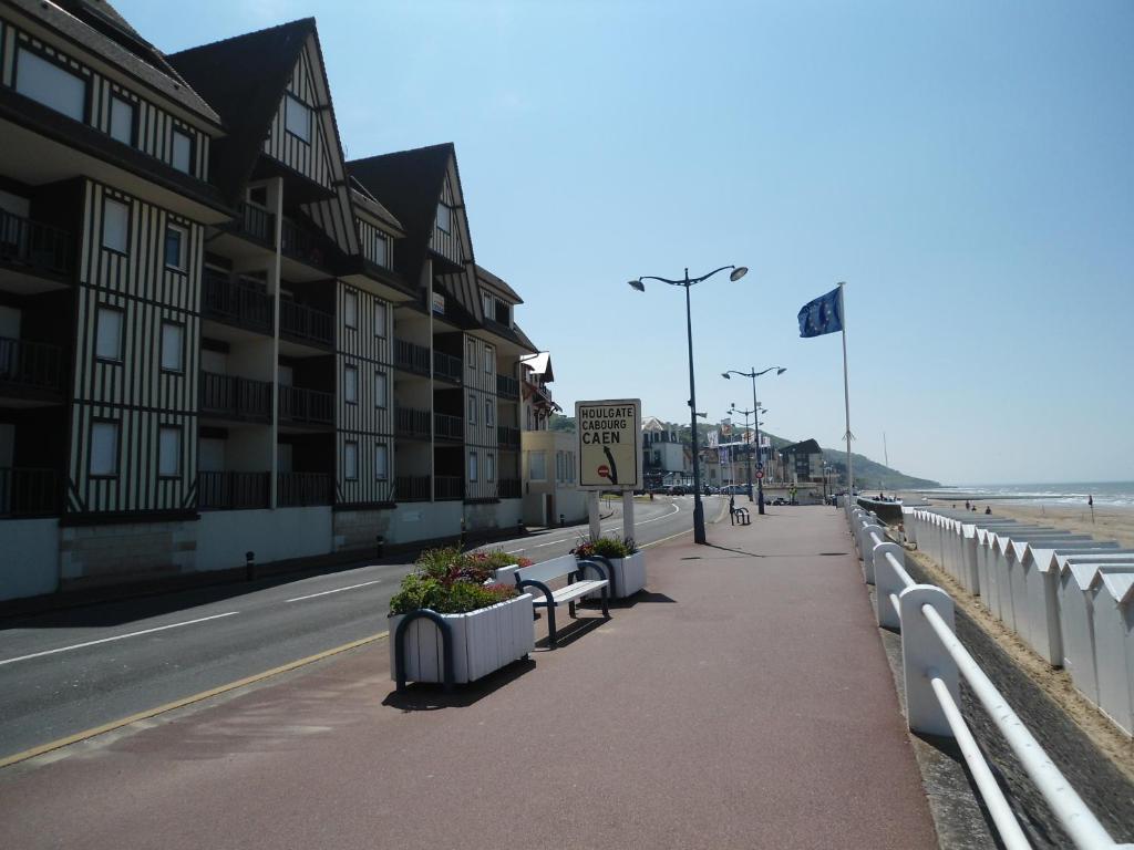 un trottoir à côté d'une plage avec des bâtiments et une rue dans l'établissement Résidence Brise de Mer, à Villers-sur-Mer