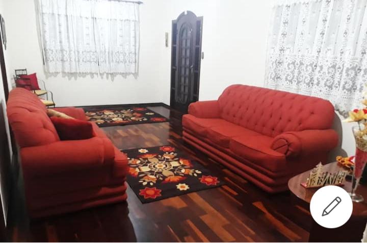 a living room with two red couches and a table at Bela Casa no Morro Chic - Itajubá - MG - Brasil in Itajubá