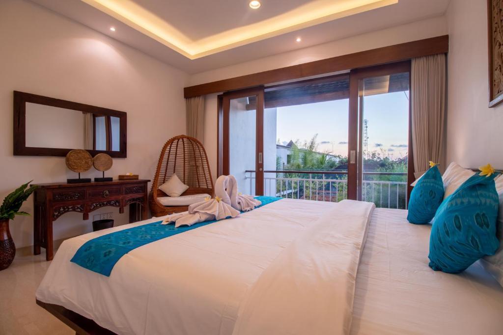 Schlafzimmer mit einem großen weißen Bett und einem Balkon in der Unterkunft Villa Sayang Sanur IV in Sanur