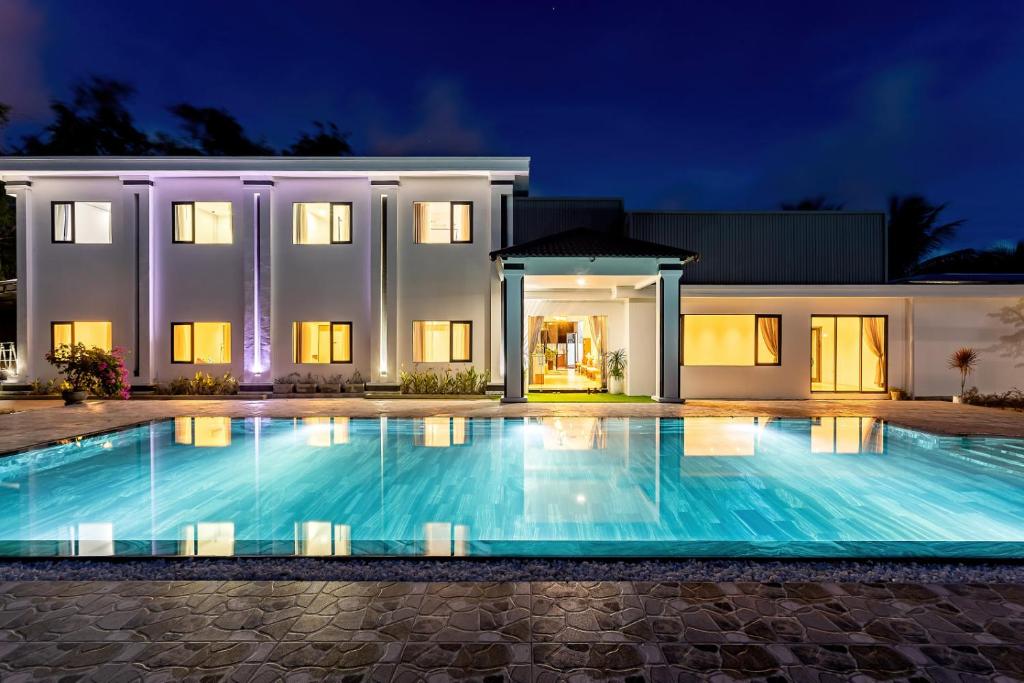 a swimming pool in front of a house at night at The Dreamers Homestay in Hue