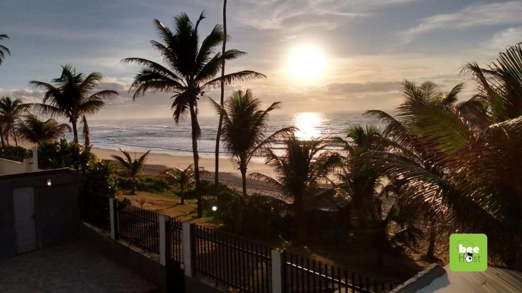 widok na plażę z palmami i słońcem w obiekcie COPFL0100 - Condomínio Recanto do Flamengo w mieście Salvador