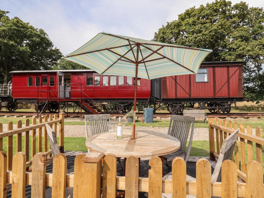 a table with an umbrella in front of a train at The Carriage at High Barn Heritage in Halstead