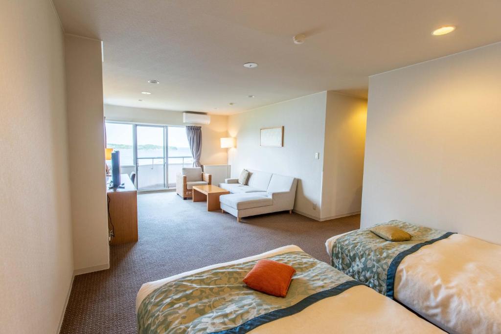 鳥羽市にあるウィスタリアンライフクラブ鳥羽  のベッド2台とリビングルームが備わるホテルルームです。