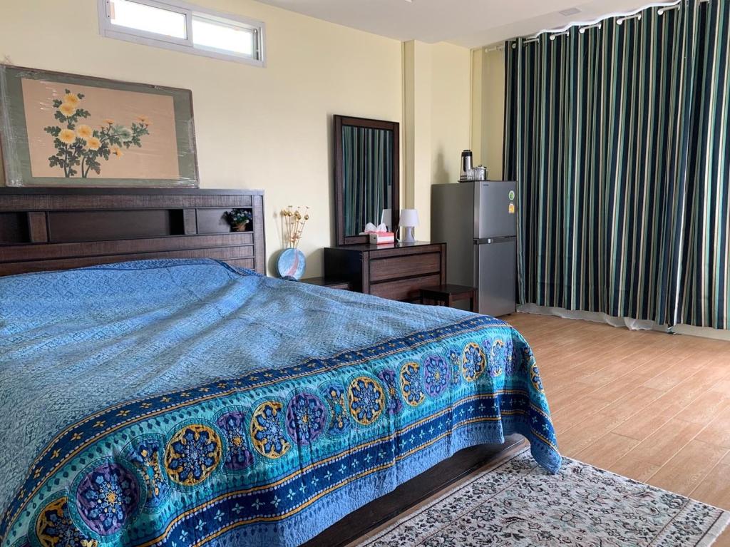 um quarto com uma cama com um cobertor azul em Gumpuju คำปู้จู้ em Chiang Mai