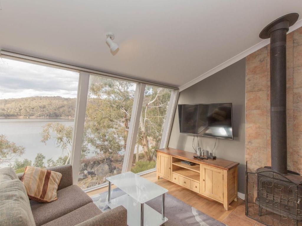 a living room with a fireplace and a large window at Dauphine 1 23 Townsend Street in Jindabyne