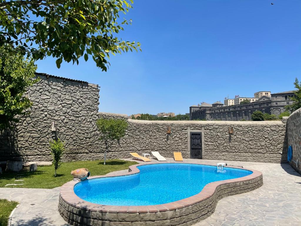 uma piscina num quintal junto a uma parede de pedra em Cozy Apartment With The Best Patio and Swimming pool em Yerevan