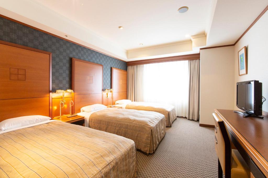 a hotel room with two beds and a television at ホテルルポール麹町 in Tokyo