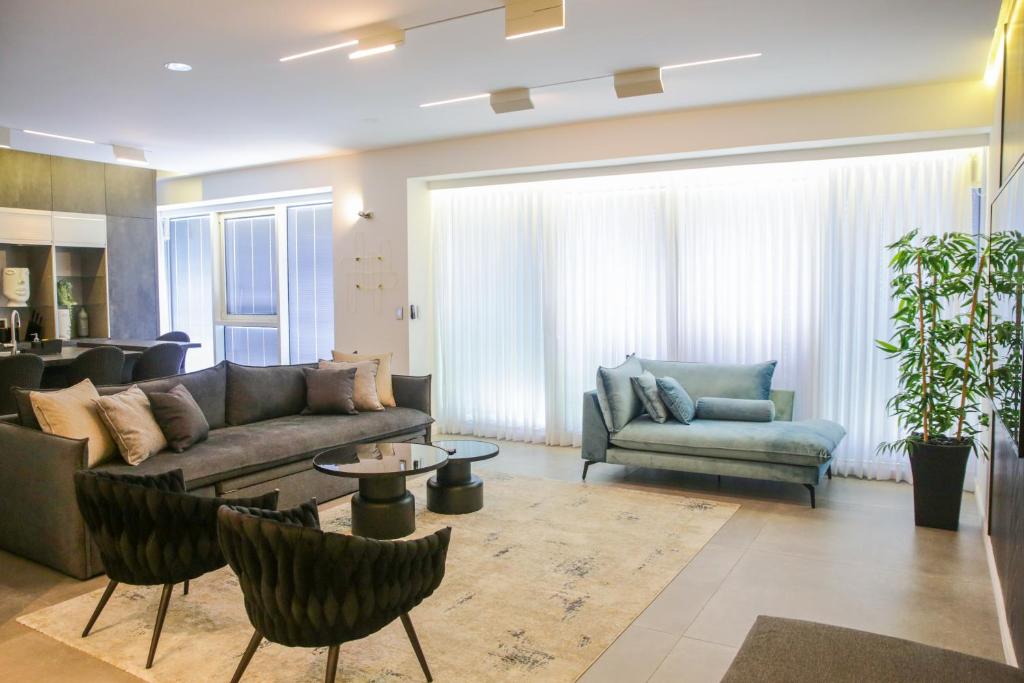 a living room with a couch and a table and chairs at YalaRent Midtown towers TLV in Tel Aviv