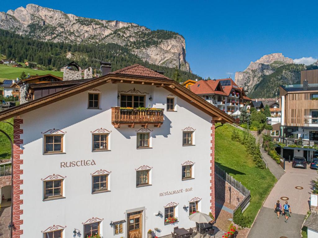 um edifício branco com uma varanda nas montanhas em Apartments Restaurant Rusctlea em Selva di Val Gardena