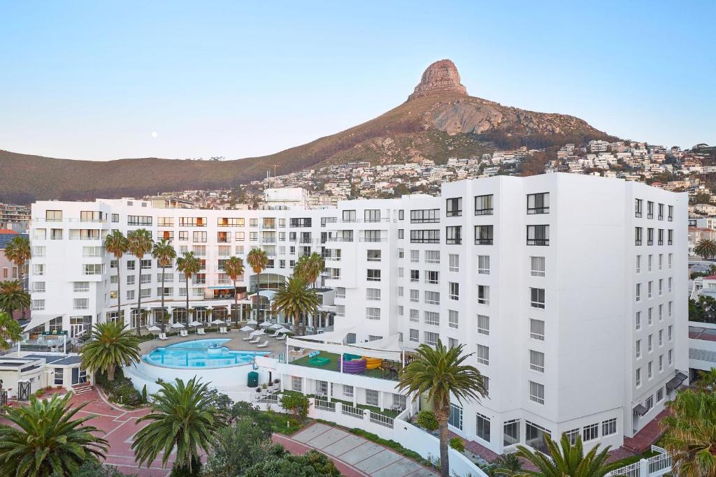 un grand bâtiment blanc avec une montagne en arrière-plan dans l'établissement President Hotel, au Cap