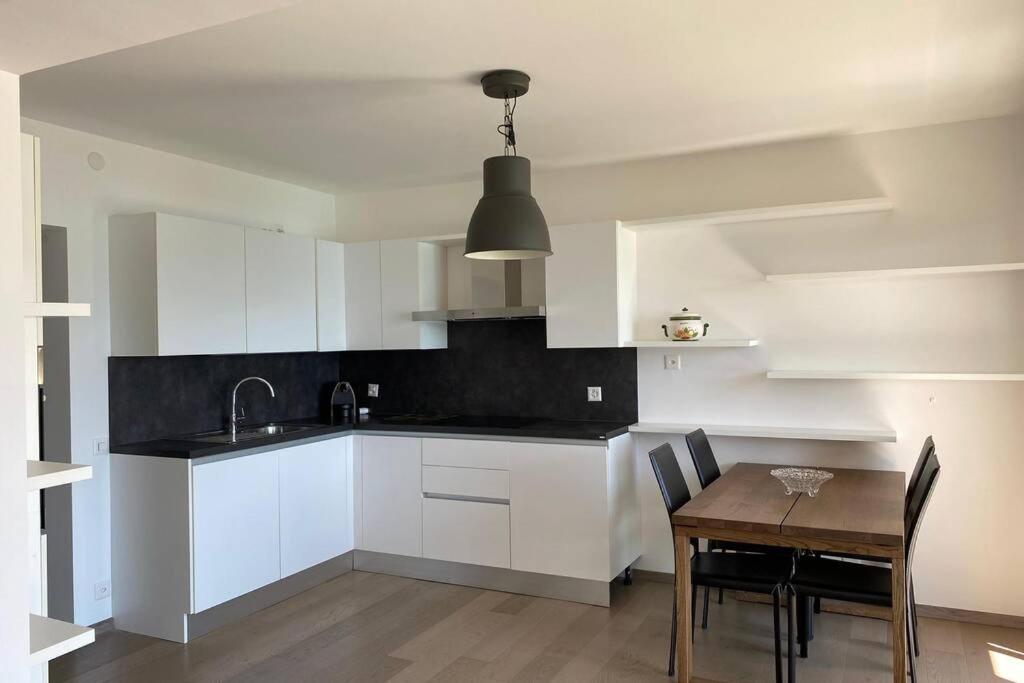 une cuisine avec des placards blancs et une table en bois dans l'établissement APNC Apartment Castagnola, à Lugano