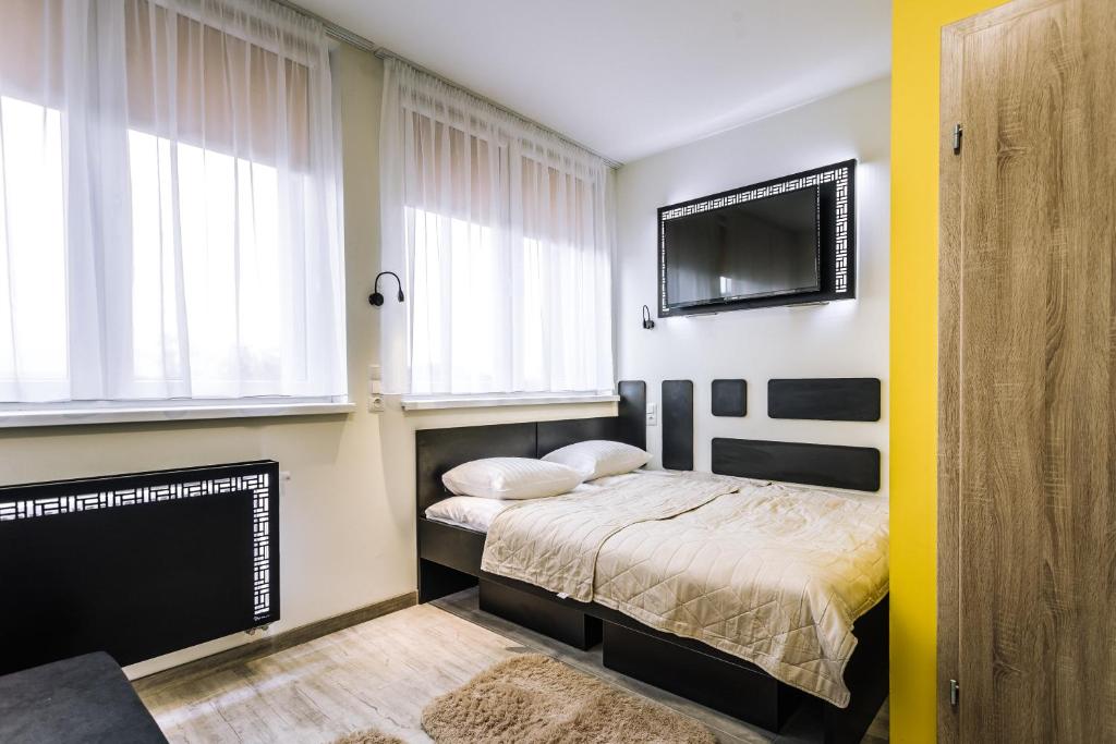 um quarto com uma cama e uma televisão de ecrã plano em Pokoje4you em Koszalin