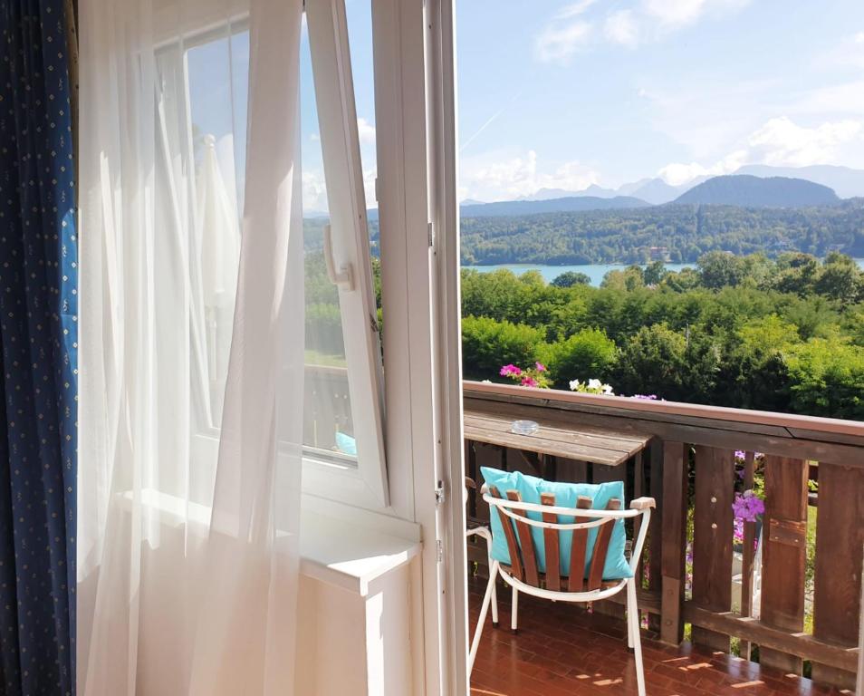 a chair on a balcony with a view of the mountains at Hotel Garni Wurzer in Velden am Wörthersee