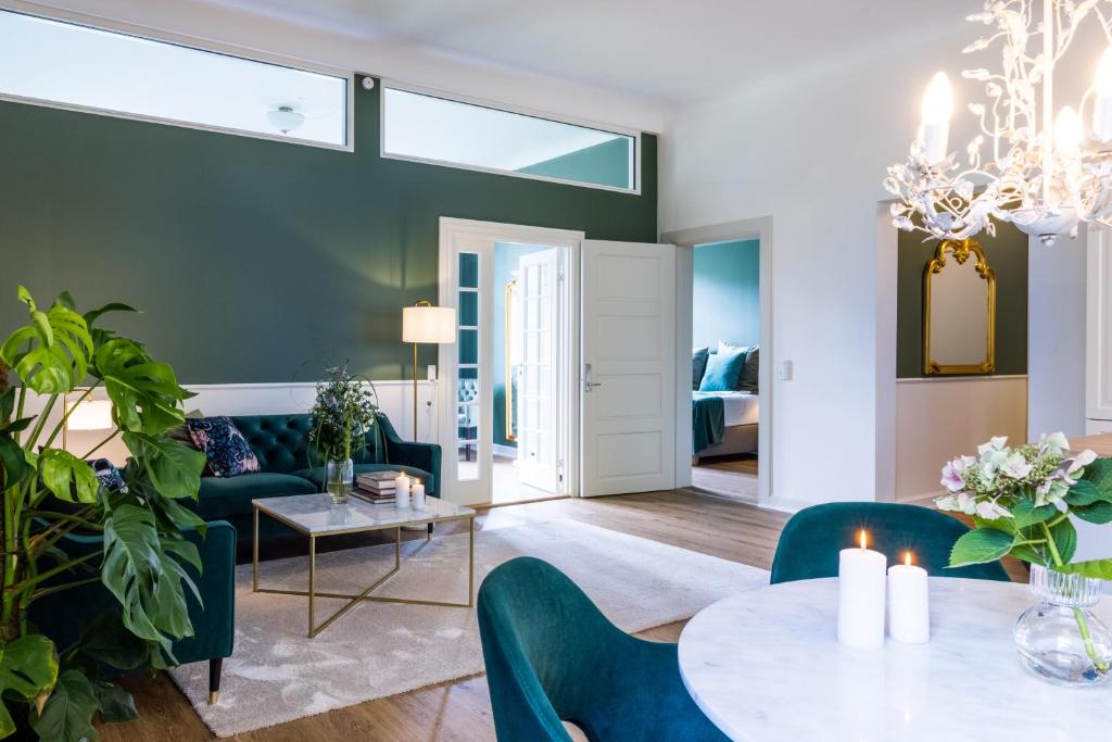 Augustenborg的住宿－'Gem Suites Luxury Holiday Apartments，客厅配有绿色椅子和桌子