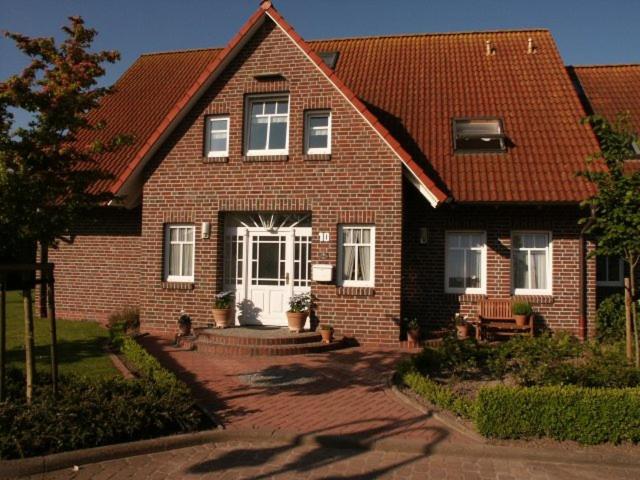 a brown brick house with a white door at Ferienwohnungen Peters in Neuharlingersiel