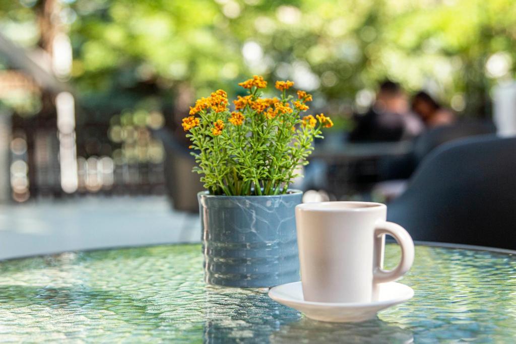 a cup of coffee and a vase with flowers on a table at Richter Pansion in Budapest