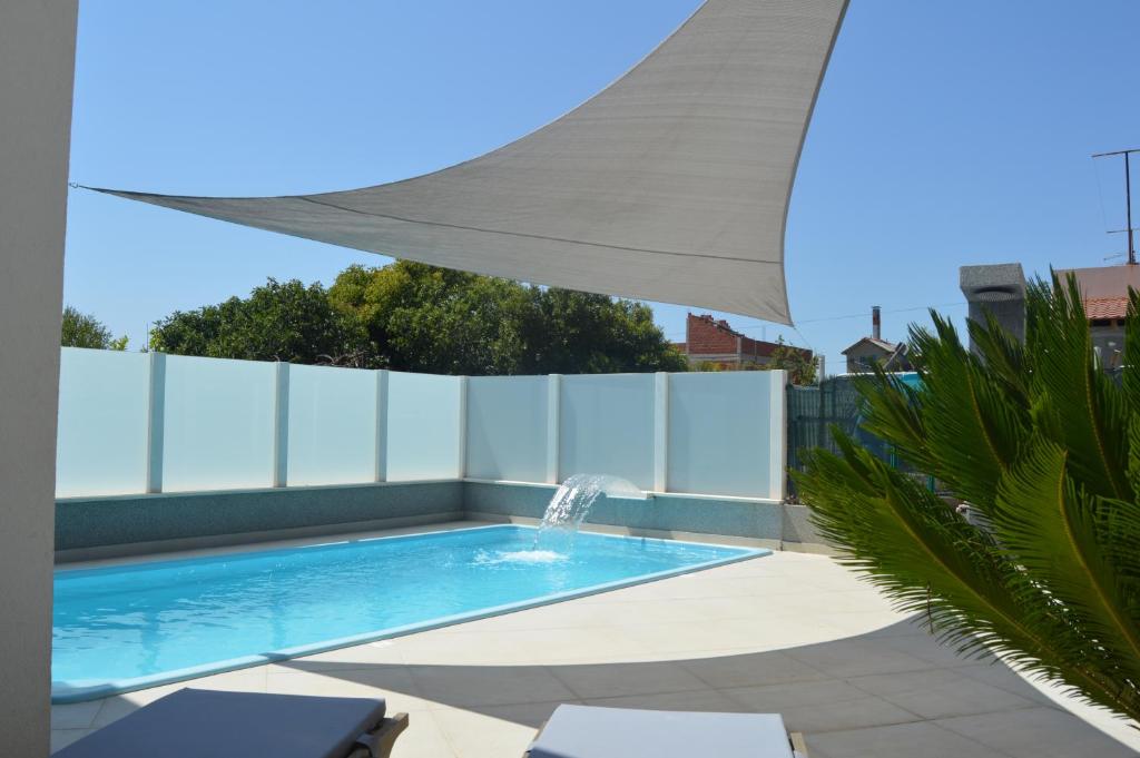 una piscina con una sombrilla blanca y una fuente en Lipa Mare, en Solin