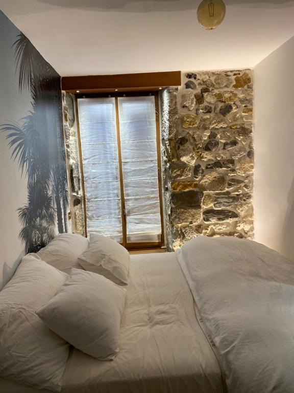 アヌシーにあるcharmant appartement Annecyの石壁と窓が特徴のドミトリールームのベッド1台分です。