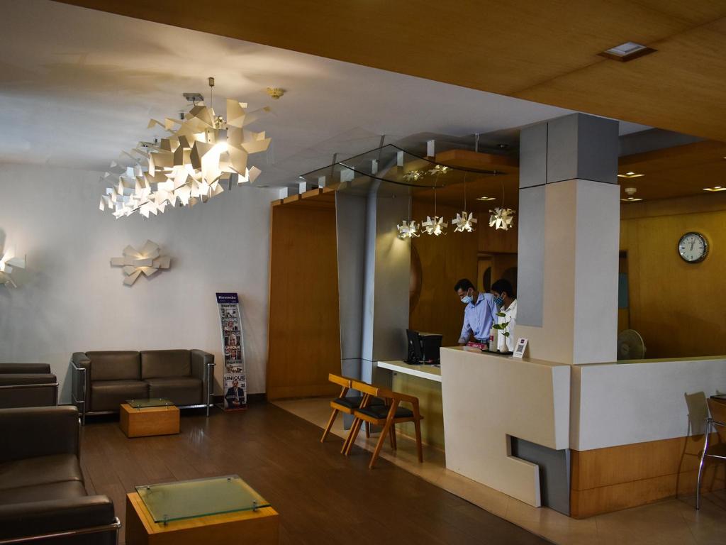 a lobby of a restaurant with a woman standing at a counter at Nexstay Asma Tower in Kozhikode