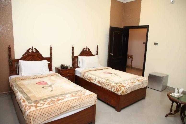 a bedroom with two beds and a television in it at Hotel OR Odyssey Residence in Multan