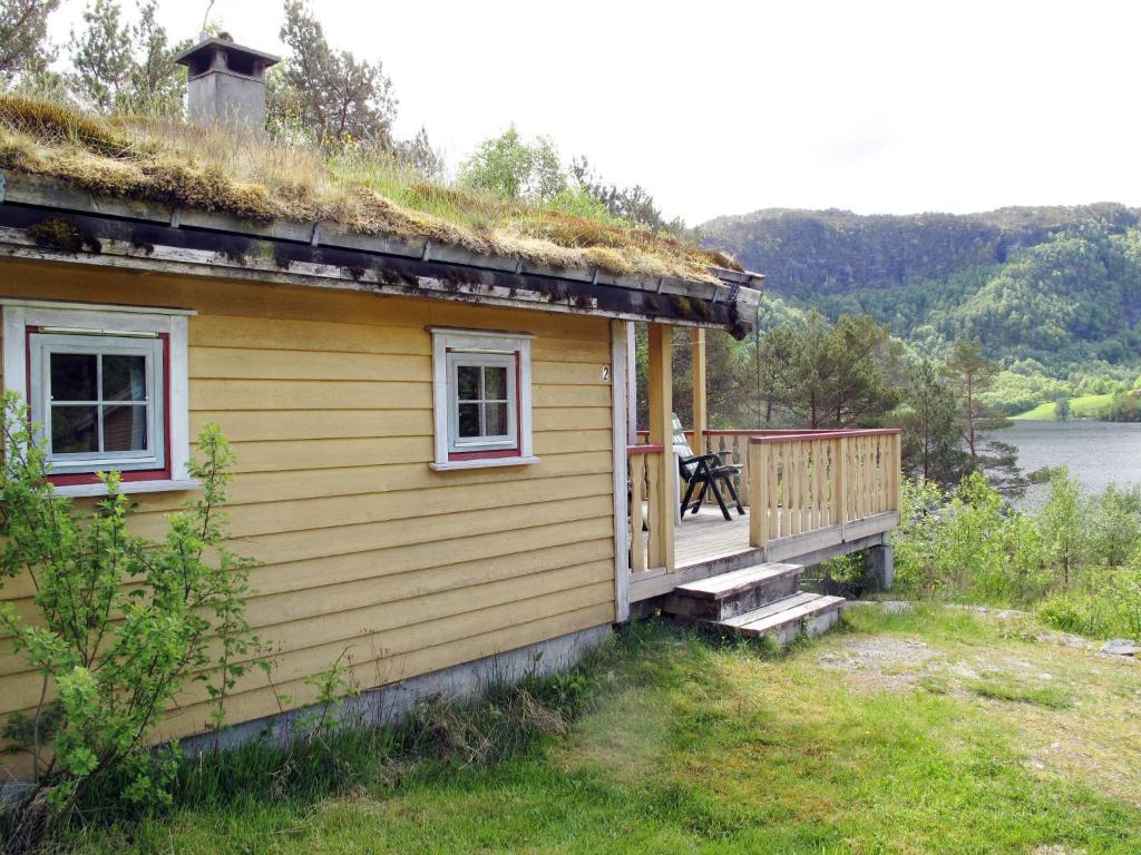 a house with a grass roof with a person sitting on the porch at Holiday Home Granlien - FJS546 by Interhome in Gjølanger