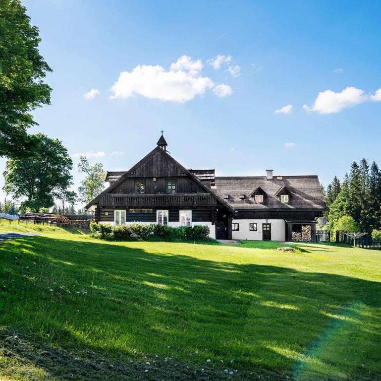 a large black and white house with a green lawn at Penzion U Churáňů in Stachy