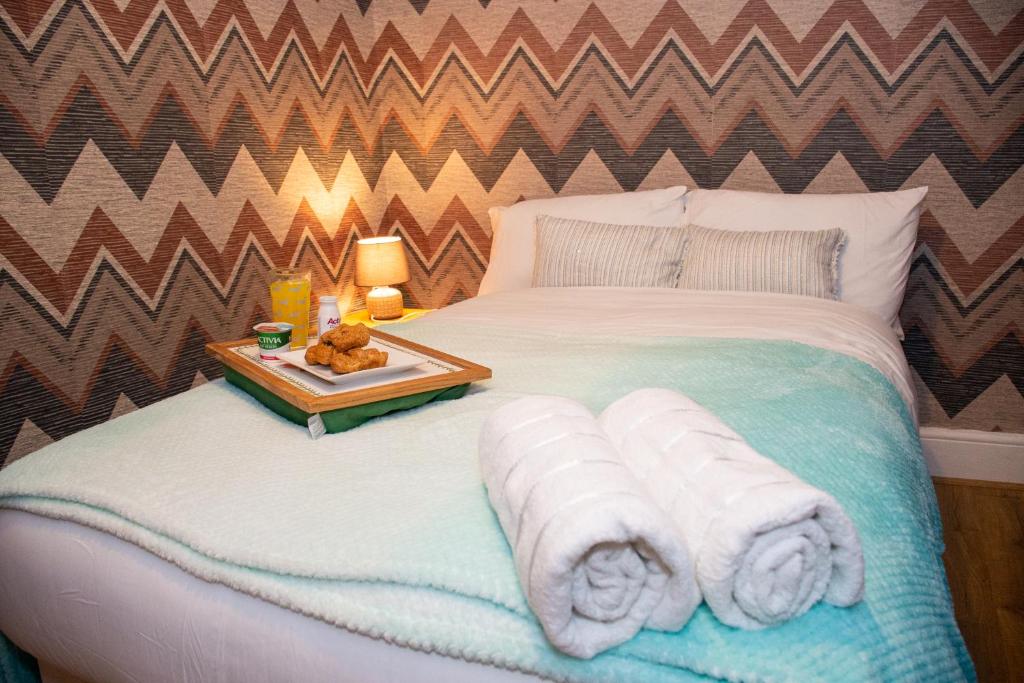 a bed with towels and a tray with a teddy bear on it at ROYALE PLACE in Northampton