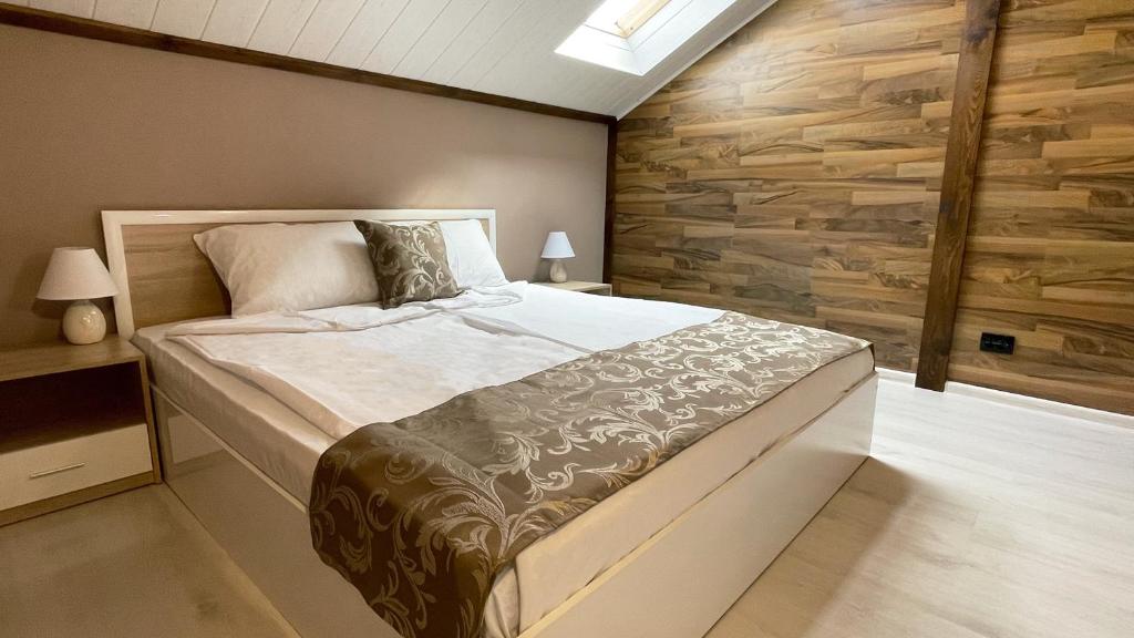 a bedroom with a large bed and a wooden wall at Апартхотел Конниците in Veliko Tŭrnovo