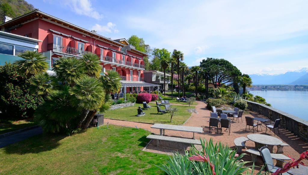 a building with tables and chairs next to a body of water at Hotel Collinetta in Ascona