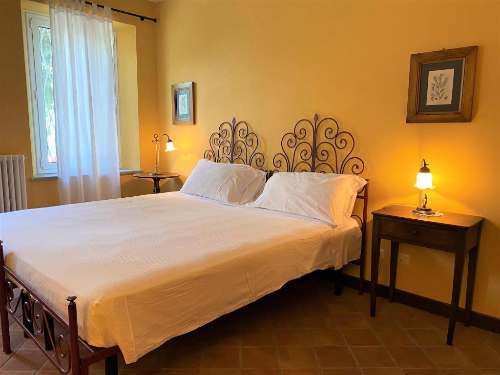1 dormitorio con 1 cama grande con sábanas blancas en B&B Tenuta Montegrande, en San Salvatore Monferrato