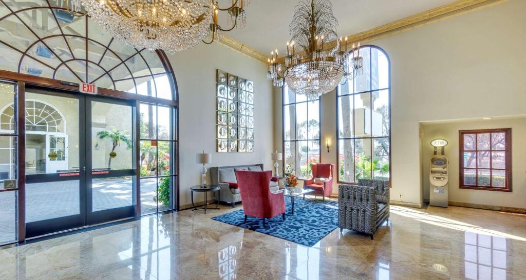 a lobby with large windows and red chairs and chandeliers at Best Western Plus Newport Mesa Inn in Costa Mesa