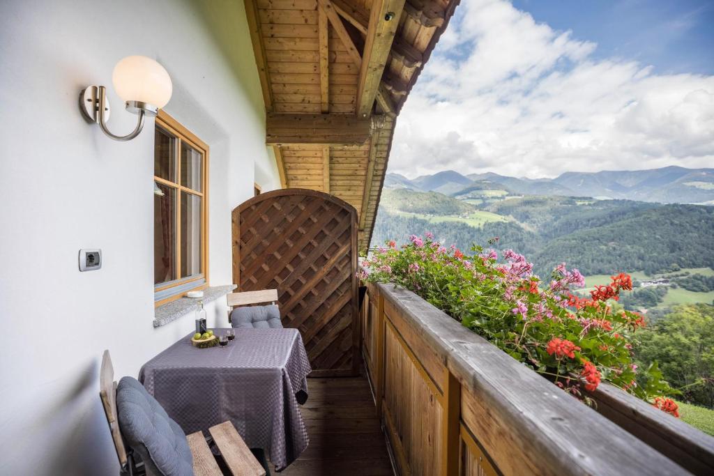 a balcony of a house with a table and flowers at Oberplunerhof - Fewo Kronplatz in Chienes