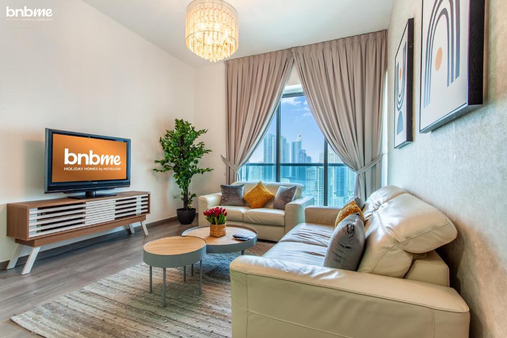 a living room with a couch and a tv at bnbmehomes - JLT Cluster P - Modern 1 BR Apt - 2506 in Dubai