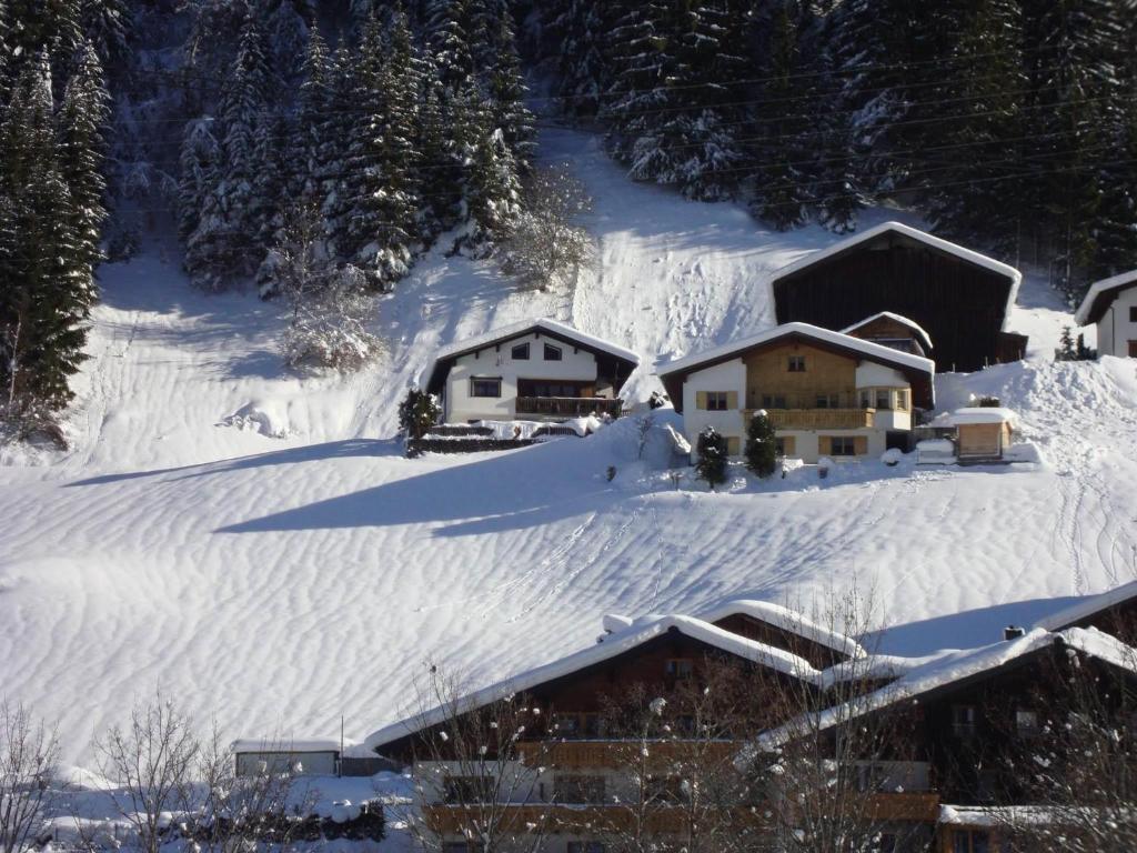 einen schneebedeckten Hang mit Häusern auf einem Berg in der Unterkunft Haus am Bühel in Gaschurn