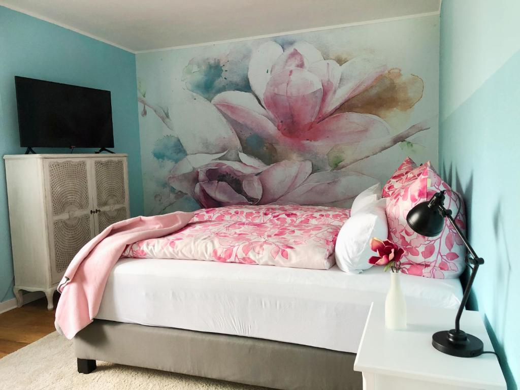 1 dormitorio con 1 cama con una pintura floral en la pared en Christianes Apartment - Ebstorf, en Ebstorf