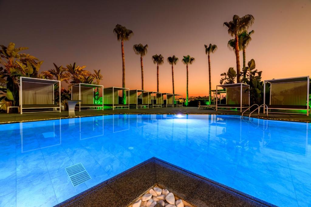 a large swimming pool with palm trees in the background at Tasia Maris Sands (Adults Only) in Ayia Napa