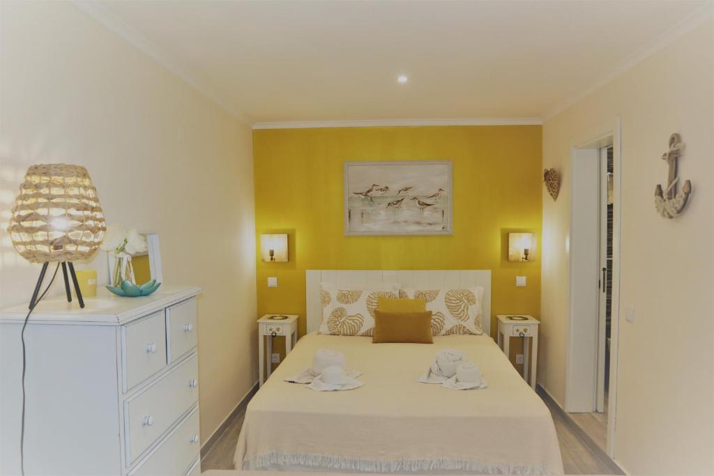 1 dormitorio con cama blanca y pared amarilla en T0 Junto a Praia de Vale Centeanes / Carvoeiro, en Lagoa