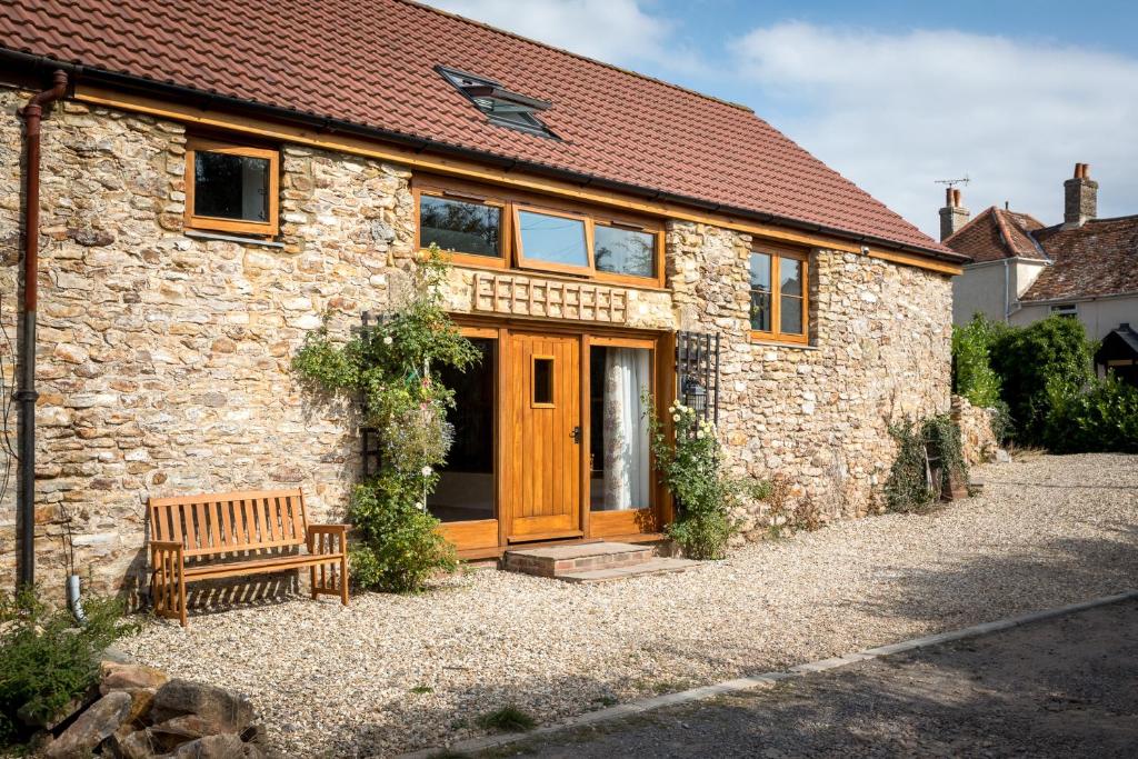 Trull的住宿－Apple Tree Barn，石头小屋,设有木门和长凳