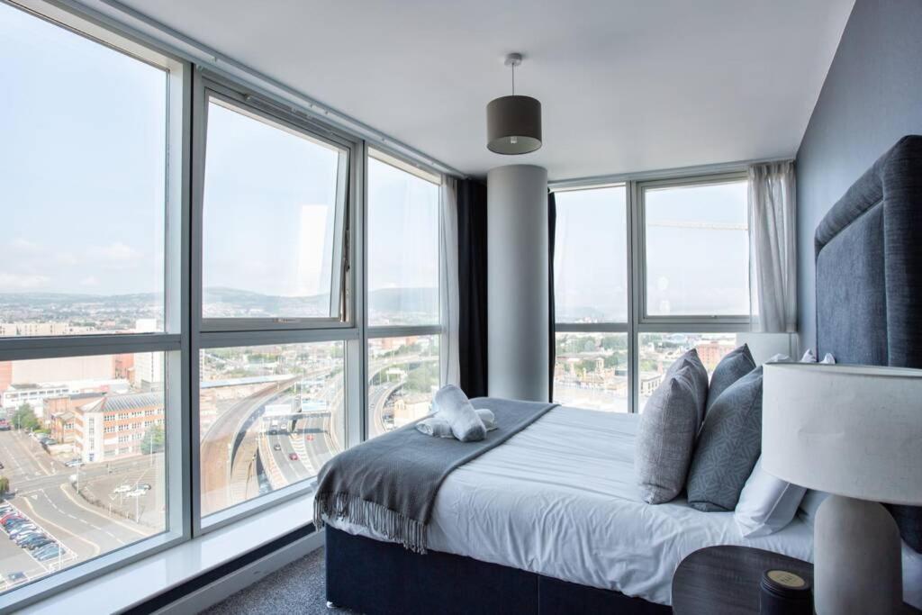 a bedroom with a bed and large windows at Titanic & City Views, Ultra Luxury City Parking in Belfast
