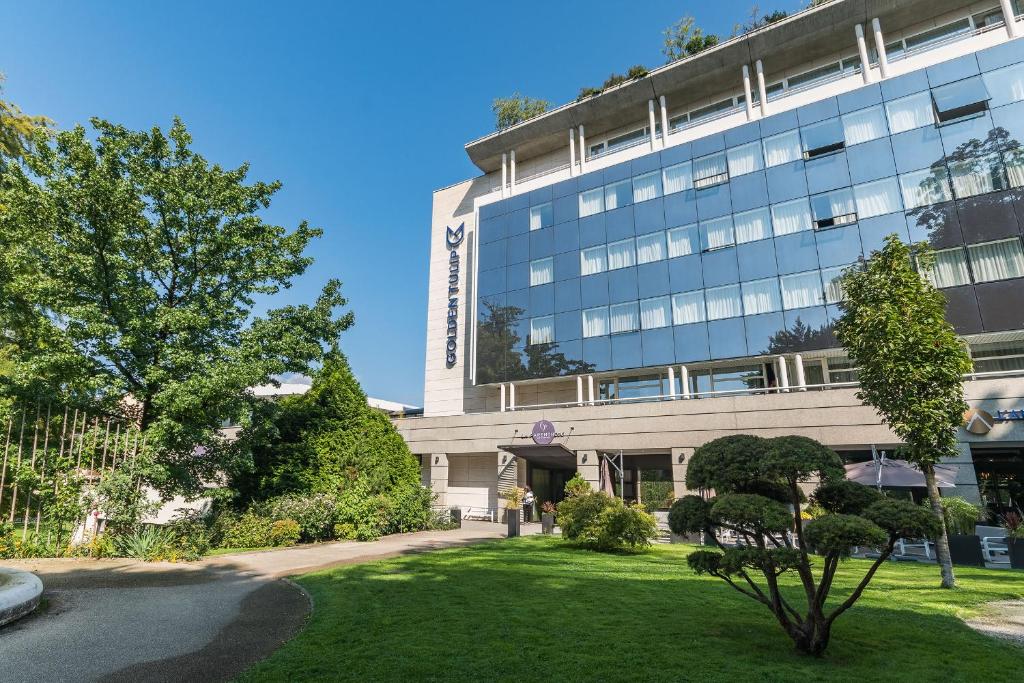 un bâtiment de bureau avec une pelouse devant lui dans l'établissement Golden Tulip Aix les Bains - Hotel & Spa, à Aix-les-Bains